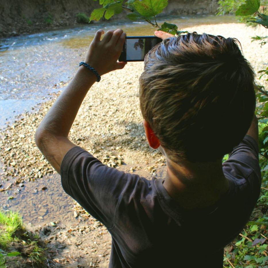 Kind fotografiert Wasserlauf mit Smartphone